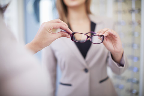 Frau beim Optiker, die eine Brille anprobiert, lizenzfreies Stockfoto