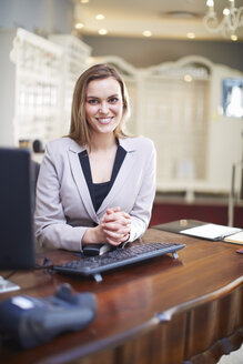 Smiling shop assustant sitting at counter - ZEF000693