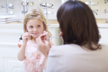 Girl at the optician trying on glasses - ZEF000591