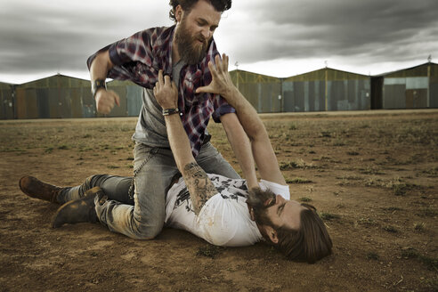 Two men with full beards fighting in abandoned landscape - KOF000029