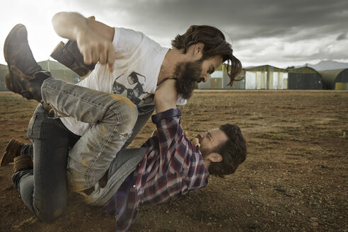 Two men with full beards fighting in abandoned landscape - KOF000030