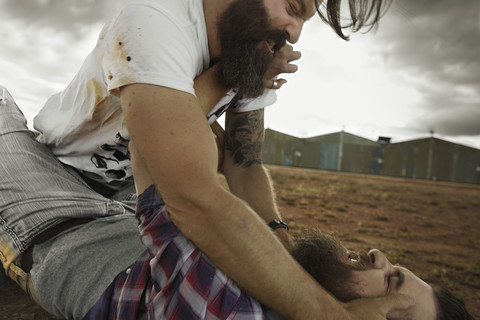 Two men with full beards fighting in abandoned landscape stock photo