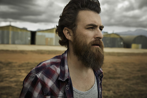 Serious man with full beard in abandoned landscape stock photo