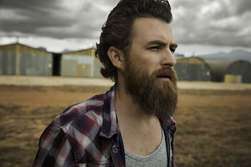 Serious man with full beard in abandoned landscape - KOF000040