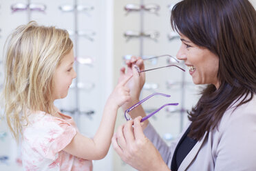 Mädchen beim Optiker, das eine Brille anprobiert - ZEF000594