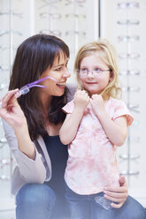 Girl at the optician trying on glasses - ZEF000595