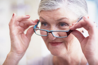 Ältere Frau beim Optiker, die eine Brille anprobiert - ZEF000746