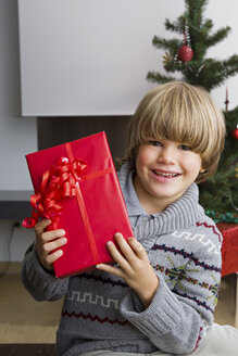 Porträt eines glücklichen kleinen Jungen mit Weihnachtsgeschenk - CHAF000188