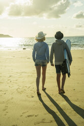 Teenage couple walking on the beach at evening twilight - UUF001698