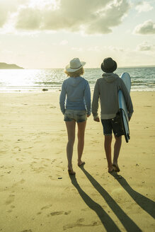 Teenager-Paar, das in der Abenddämmerung am Strand spazieren geht - UUF001698