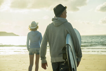 Teenage couple walking on the beach at evening twilight - UUF001752