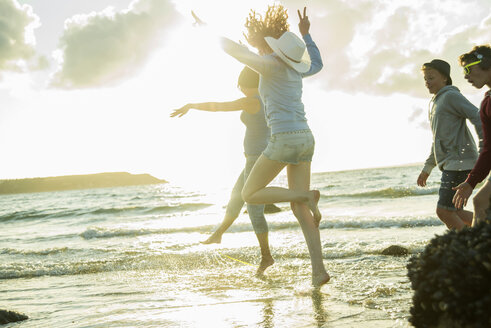 Frau und drei Teenager haben Spaß am Strand bei Sonnenuntergang - UUF001714