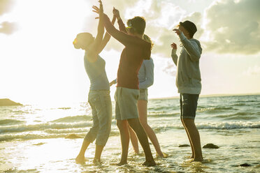 Woman and three teenagers having fun on the beach by sunset - UUF001715