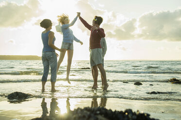 Frau und drei Teenager haben Spaß am Strand bei Sonnenuntergang - UUF001716
