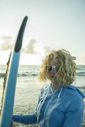 Porträt eines jungen Mädchens am Strand mit ihrem Surfbrett - UUF001726