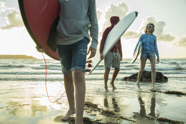 Drei Jugendliche mit Surfbrettern spazieren am Ufer des Meeres - UUF001734