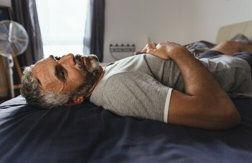 Pensive man lying on his bed at daytime - MBEF001147