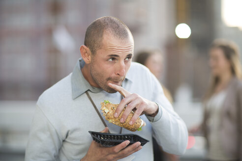 Portrait of businessman eating sandwich at lunchtime - ZEF000219