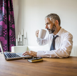 Porträt eines Geschäftsmannes, der zu Hause im Büro arbeitet und Kaffee trinkt - MBEF001232