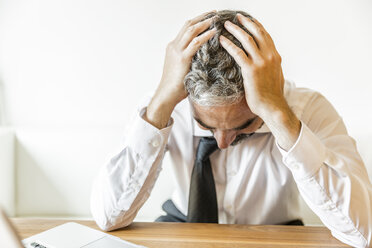 Overstressed businessman with head in his hands - MBEF001153