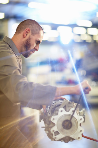 Automechaniker bei der Arbeit am Getriebe in einer Reparaturwerkstatt, lizenzfreies Stockfoto