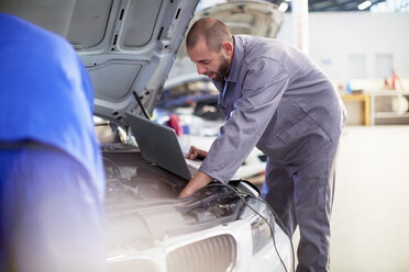 Two car mechanics at work in repair garage - ZEF000848