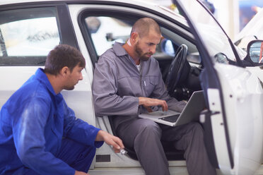 Two car mechanics with laptop in repair garage - ZEF000511