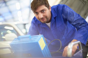 Lächelnder Automechaniker in einer Reparaturwerkstatt - ZEF000518