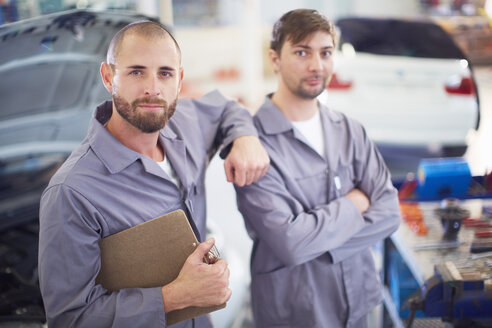 Zwei Automechaniker mit Klemmbrettern in einer Reparaturwerkstatt - ZEF000522