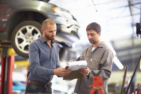 Automechaniker mit einem Kunden in einer Reparaturwerkstatt - ZEF000553