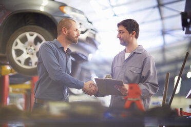 Automechaniker und Kunde schütteln sich in der Werkstatt die Hände - ZEF000695