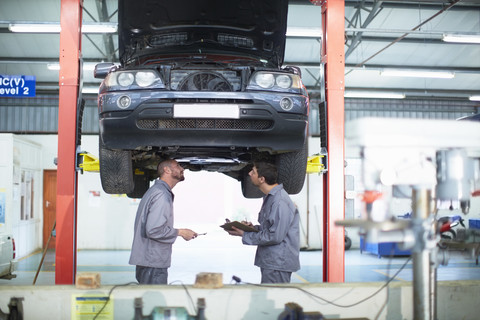 Zwei Automechaniker bei der Arbeit in einer Reparaturwerkstatt, lizenzfreies Stockfoto