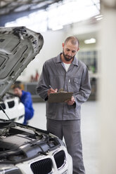 Automechaniker mit Klemmbrett in einer Reparaturwerkstatt - ZEF000570