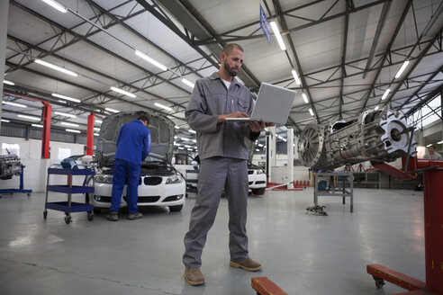 Two car mechanics with laptop in repair garage - ZEF000736