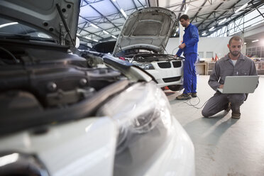 Zwei Automechaniker mit Laptop in der Reparaturwerkstatt - ZEF000737