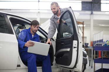 Two car mechanics with laptop in repair garage - ZEF000578