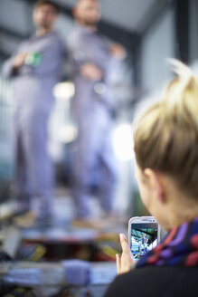 Frau macht Handyfoto von Arbeitern in einer Fabrik - ZEF000586