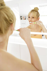 Frau betrachtet ihr Spiegelbild beim Zähneputzen - GDF000426