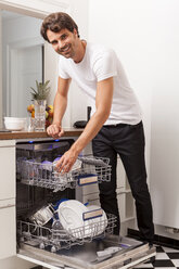 Smiling young man emptying the dishwasher - JUNF000036