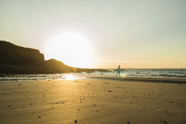 France, Brittany, Camaret-sur-Mer, surfer on the beach at sunset - UUF001803