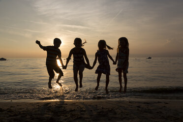 Italien, Gardasee, Kinder springen bei Sonnenuntergang am Strand - SARF000842