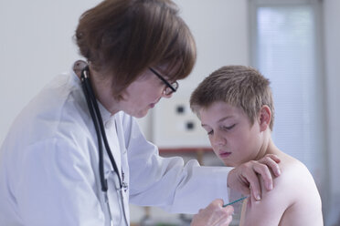 Arzt verabreicht einem Jungen eine Spritze in einer Arztpraxis - SGF000840