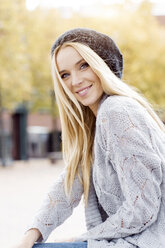 Portrait of smiling young woman wearing wooly hat and cardigan - GDF000444
