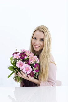 Porträt einer lächelnden jungen Frau, die einen Blumenstrauß hält - GDF000452