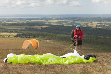 France, Bretagne, Finistere, man packing his paraglider - LAF001034