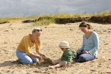 France, Britanny, Sainte-Anne-la-Palud, mother and her two daughters sitting on beach dune - LAF001140