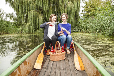 Zwei junge Frauen im Ruderboot mit Flasche und Glas - DISF001029