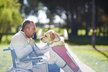 Man in wheelchair with dog in park - ZEF000386