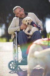 Mann im Rollstuhl mit Hundewelpe im Park - ZEF000397