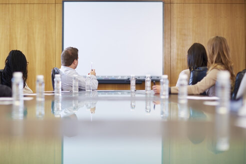 Gruppe von Geschäftsleuten, die eine leere Tafel im Sitzungssaal betrachten - ZEF000266